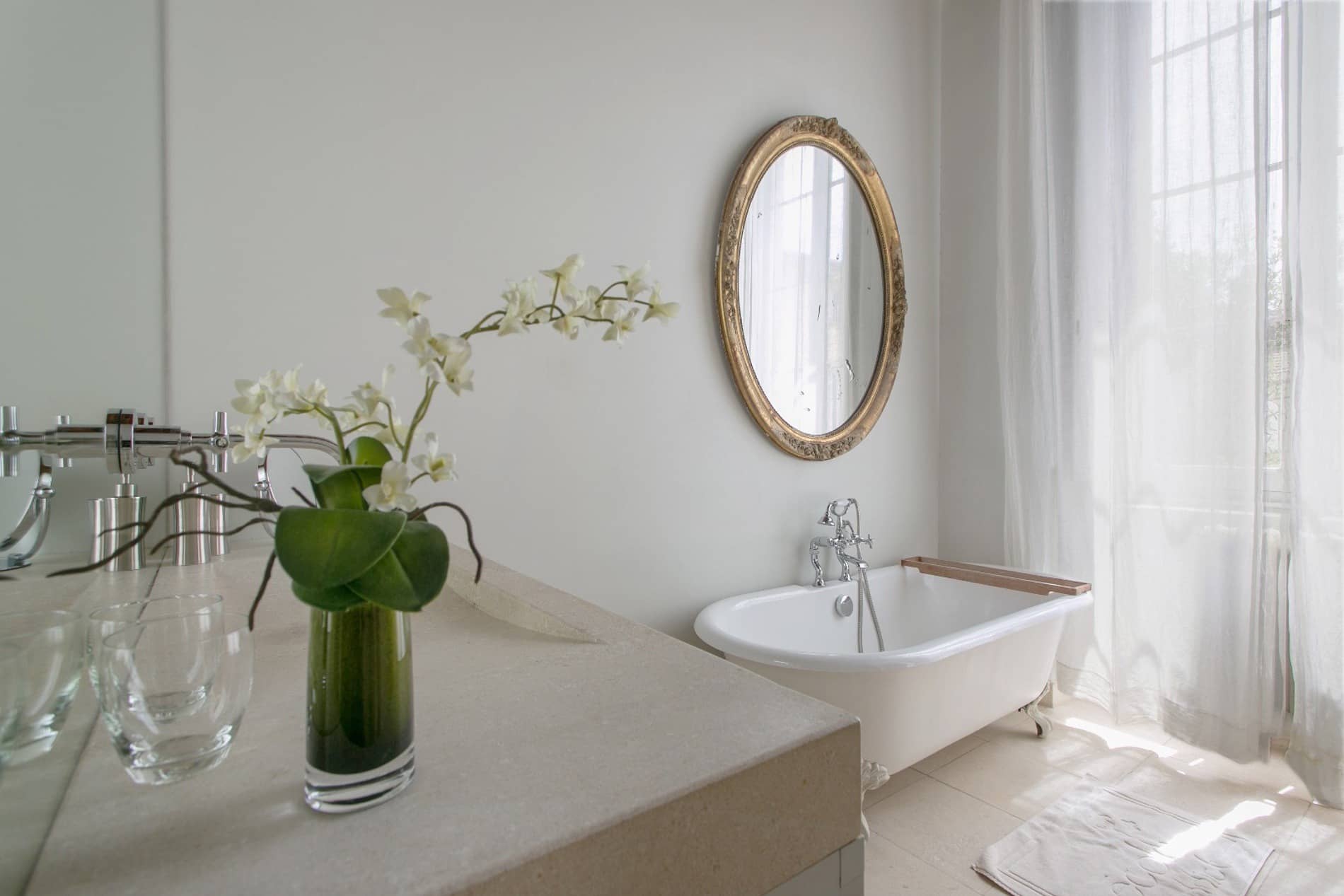 Salle de bain élégante avec baignoire sur pieds et miroir ovale dans une suite du Château